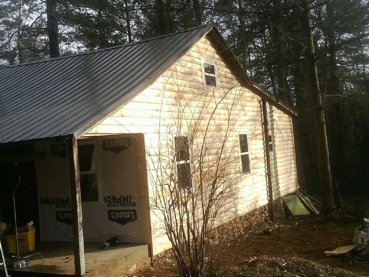 Log siding gable end under a dark metal roof edge in Elkmont