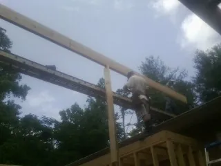 Carpenter setting a ridge beam over a new addition frame — Ice Dam Removal by Roofing Brothers in Elkmont