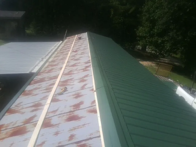 Old rusted panels beside newly installed green metal roofing — Wind Damage Roof Repair by Roofing Brothers in Elkmont
