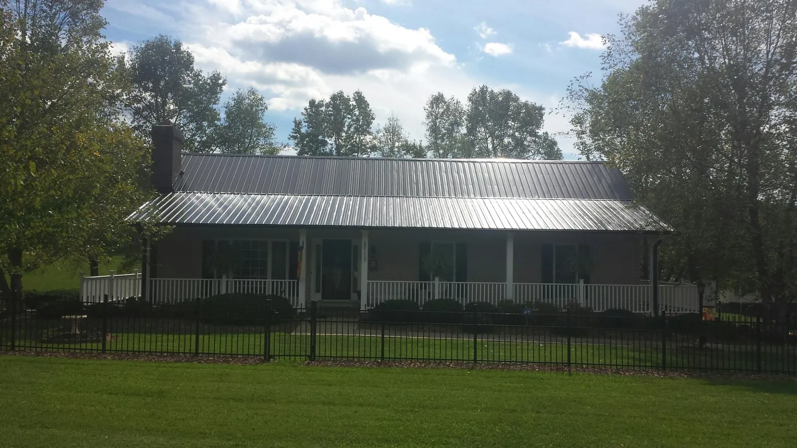 Gray metal roof on a brick ranch with a full width front porch — Gutter Guard Installation work by our crew in Elkmont