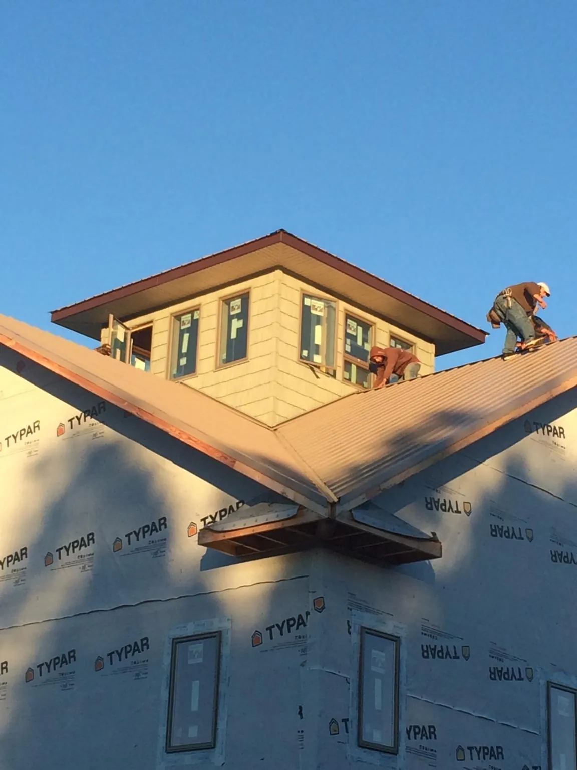 Roofers working around a rooftop cupola on a new metal roof at sunset — Roof Waterproofing in Elkmont by Roofing Brothers